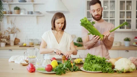 Young couple cooking together preparing dinner chopping vegetables and talking Stock Footage 146277834