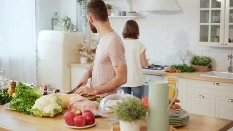 Young couple cooking together preparing dinner chopping vegetables and talking Stock Footage 146277852