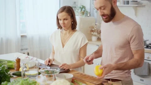 Young couple cooking together preparing dinner and talking at home Stock Footage 146278170