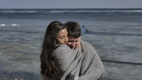 Young couple cuddling,in background a river covered with ice,sunny spring day Stock Footage 124427354