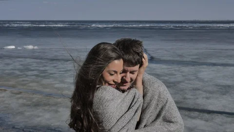 Young couple cuddling,in background a river covered with ice,sunny spring day Stock Footage 124427407