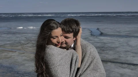Young couple cuddling,in background a river covered with ice,sunny spring day Stock Footage 124427495