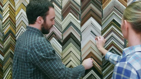 Young couple customer looking for frame for picture in atelier Vídeo Stock 114776704