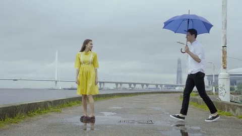 Young couple dance swiftly under umbrella on a pier on a sea coast Stock Footage 80198190