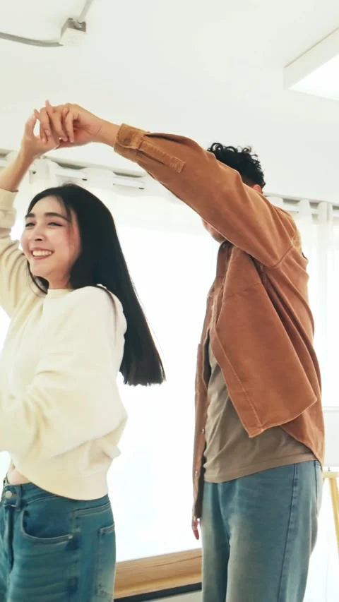 A young couple dances joyfully in a bright room, smiling and enjoying each other Stock-Footage 328076876