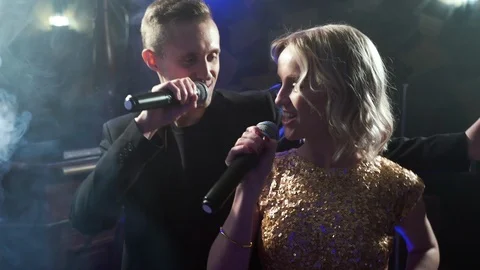 Young couple dancing and singing with a microphone in a karaoke bar Stock Footage 107827946
