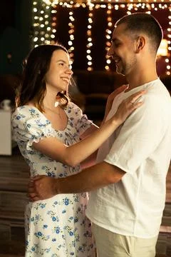 Young couple dancing intimately under warm string lights at night Stock Photos