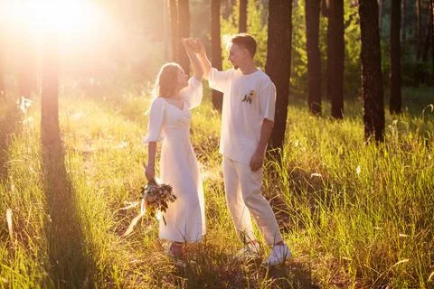 Young couple dancing in a sun-drenched forest with tall grass Stock Photos