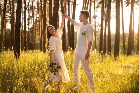 Young couple dancing in a sunlit forest meadow during golden hour Stock Photos