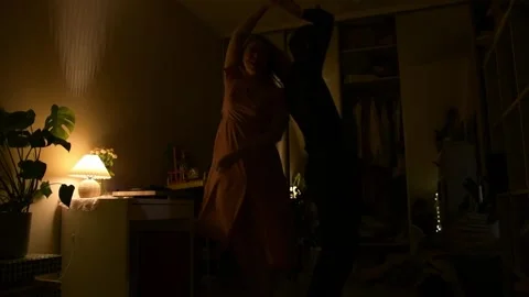 Young couple dancing together in a dimly lit room during the evening. 库存影片 330800634