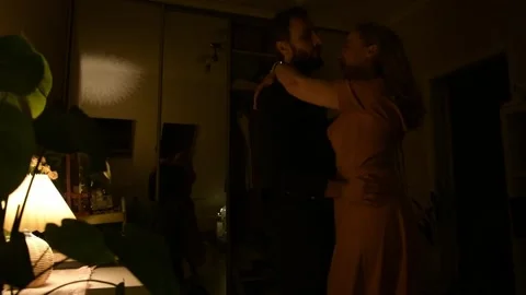 Young couple dancing together in a dimly lit room during the evening. 库存影片 330800699