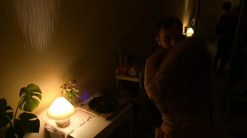 Young couple dancing together in a dimly lit room during the evening. 库存影片 330800789