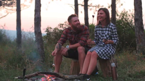 Young couple on a date in the forest to roast marshmallows in the fire Stock Footage 66486042