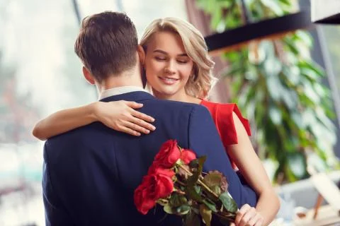 Young couple on date in restaurant dancing holding bouquet woman closed eyes Stock Photos