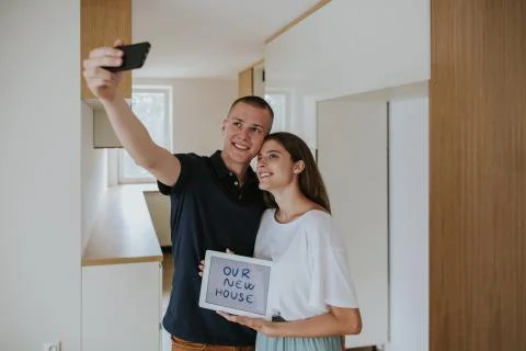 Young couple with digital tablet taking selfie in new house. Stock Photos
