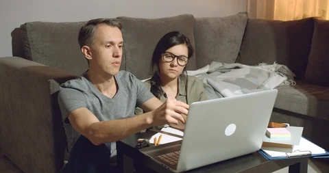 Young couple discussing a joint project working on a laptop at home Stock Footage 129898606