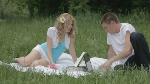 Young couple disputing with opened book and laptop on grass Stock-Footage 7766959
