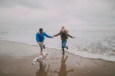 Young Couple Dodge Waves On Winter Beach Photos