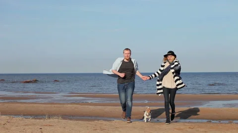 Young couple with a dog run on the beach 스톡 동영상 62918199