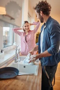 A young couple doing housework in the kitchen together. Kitchen, housework, h Stock Photos