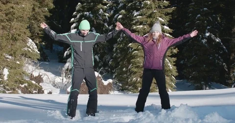 Young couple doing jumping jacks in the middle of a snowy forest Vídeo Stock 85070360