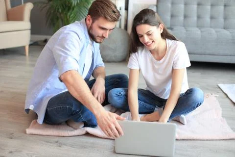 Young couple doing some online shopping at home, using a laptop on floor. Stockfoto's