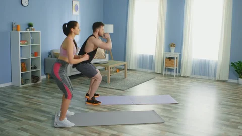 Young Couple Is Doing Squats at Home Vídeos de archivo 129742590