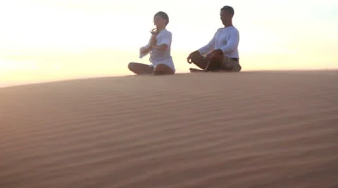 Young couple doing yoga exercises on a desert at sunrise or sunset Видео 22786941