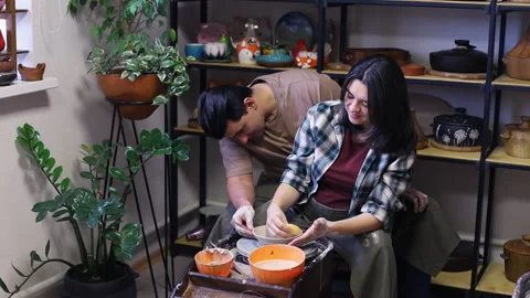 Young couple draws a simple pattern and soaks a clay cup Stock Footage 165555140