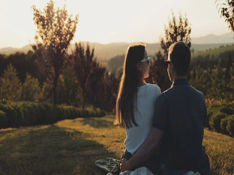 Young Couple Dream about Future in Fairytale Garden at Sunset. SLOW MOTION 4K. Stock Footage