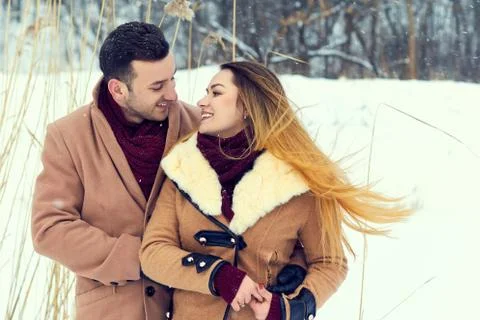 Young couple, dressed in coats and scarves walks on nature in winter Stock Photos