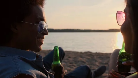 Young couple drinking beer on the beach  Stock-Footage 115823326