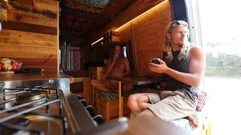 Young couple drinking coffee in alternative camper van Stock Footage 114786365