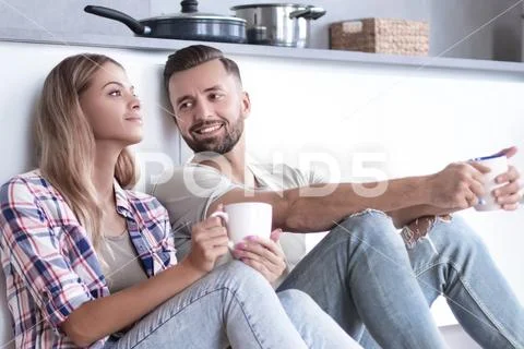 Young couple drinking coffee sitting on the kitchen floor Stock Photos