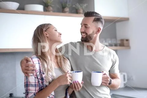 Young couple drinking coffee standing in the kitchen Stock Photos