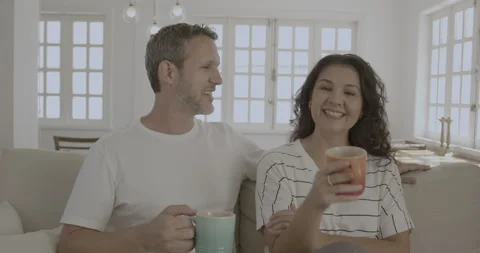 Young couple drinking coffee, talking on the sofa. Stock Footage 232436206