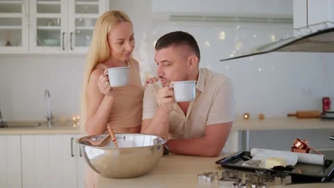Young couple drinking hot chocolate while making dough for Christmas cookies. Stock Footage 166523834