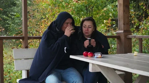 A young couple is drinking tea sitting on the street under a blanket and in warm Stock Footage 170821801