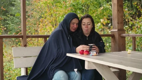 A young couple is drinking tea sitting on the street under a blanket and in warm Stock Footage 172257817