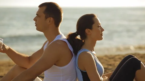 Young couple drinking water on beach Stock Footage 43620119