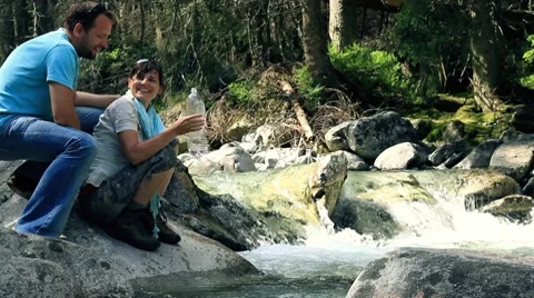 Young couple drinking water from river in the mountains Stock Footage 7907476