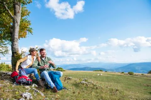 Young couple drinking water while resting on the rock during the travel in the Stock Photos