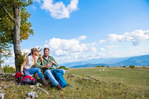 Young couple drinking water while resting on the rock during the travel in the Stock Photos