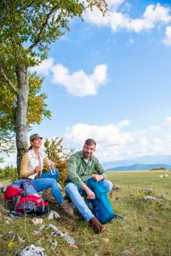 Young couple drinking water while resting on the rock during the travel in the Stock Photos