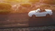 Young Couple Driving Convertible Car At Sunset By The Sea Front Beach Aerial Fly Stock Footage