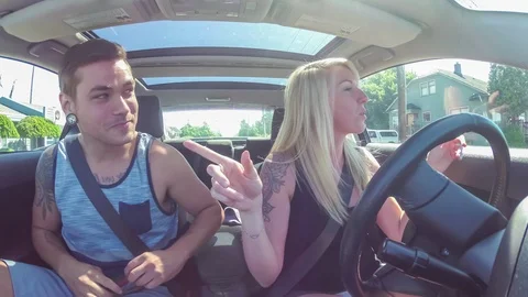 Young couple driving through a city neighborhood searching for an address Stock Footage 92604119