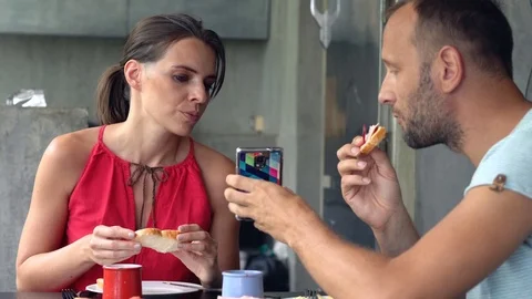 Young couple during breakfast, man showing  smartphone his girlfriend Stock Footage 73145627