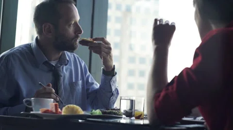 Young couple eating breakfast by table close to the window with city view Stock Footage 60736179