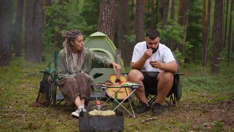 Young couple eating together while camping in the forest Stock Footage 327530188
