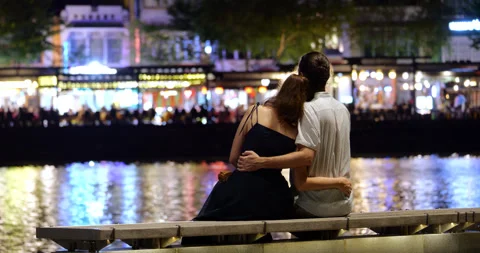 Young couple embracing on bench, sit at Singapore River at night Stock Footage 306582835